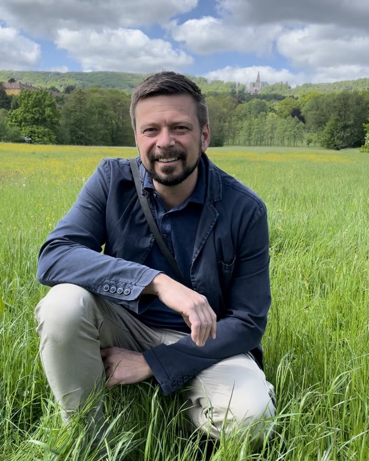 Felix Kraft auf einer Wiese in Kassel, im Hintergrund der Herkules